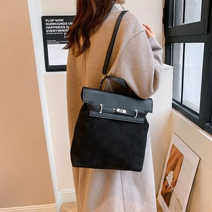 Detail view of black faux suede and leather handbag with silver twist-lock closure