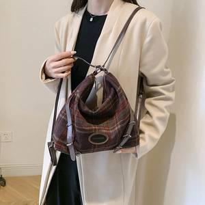 Détail du sac à bandoulière rétro en tweed à carreaux rouge et vert avec écusson en cuir