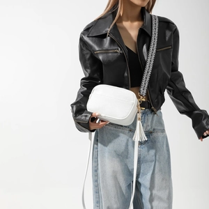 Détail du sac bandoulière blanc avec texture litchi, pompon et large sangle géométrique