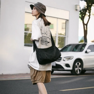 Street style shot of a spacious black nylon crescent crossbody bag worn by a model