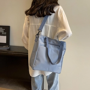Vue détaillée du sac fourre-tout bleu gris imperméable porté par un mannequin en intérieur