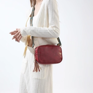 Sac bandoulière bordeaux chic avec sangle ethnique et pompon sur tenue blanche