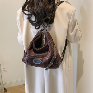 Vue détaillée du sac à dos vintage en laine à carreaux avec lanières en cuir et logo