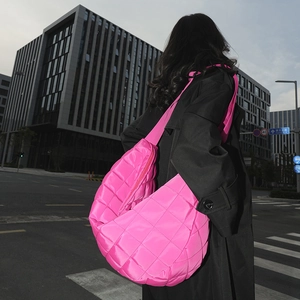 Vue détaillée du sac hobo en nylon matelassé rose fluo porté par un mannequin en ville