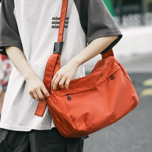 Close-up of vibrant orange nylon messenger bag featuring signature round ring zippers