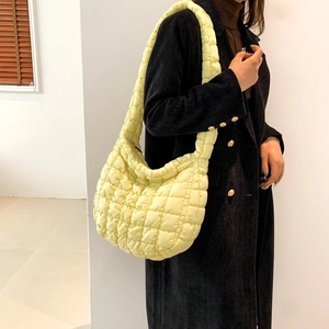 Close-up of bright yellow quilted puffer crossbody bag with large capacity crescent shape