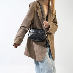 Detail of minimalist black PU underarm bag featuring vintage texture and long tassel charm
