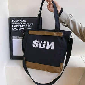 Detail of black and brown canvas tote bag with SÜN print and removable shoulder strap
