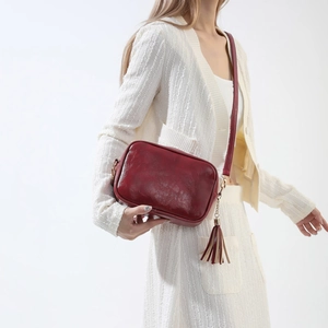 Sac caméra bordeaux rétro en cuir huilé avec bandoulière large et détail de pompon