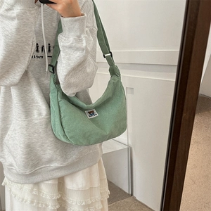 Detailed close-up of light green corduroy hobo bag with cute bear patch and adjustable strap