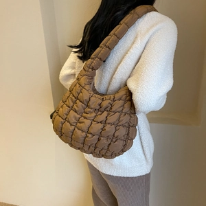 Sac à bandoulière matelassé marron présenté dans une scène de tenue de rue