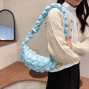 Détail du sac lune matelassé bleu clair avec bandoulière plissée porté par un mannequin