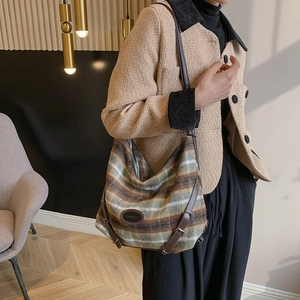 Vue détaillée de la texture du tweed rayé et du badge en cuir tendance sur le sac à main
