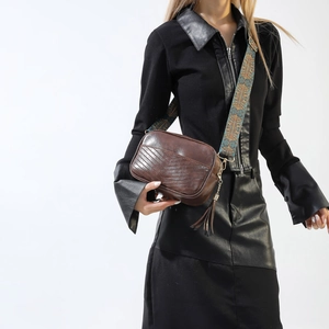 Detail of dark brown leather crossbody bag with V-quilt pattern and woven boho strap