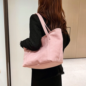 Detailed view of pink textured tote bag with wide shoulder strap worn by a model