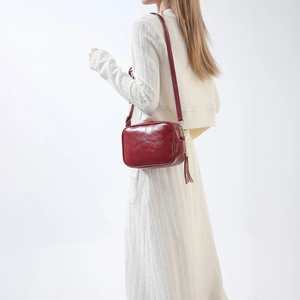 Vue détaillée d'un sac bandoulière vintage en similicuir rouge avec pompon décoratif