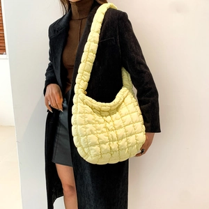 Detail of lemon yellow quilted bubble hobo bag with puffer texture on a model