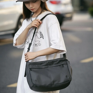 Detailed view of dark grey nylon crossbody bag with zipper pockets and adjustable strap