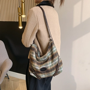 Gros plan du sac cabas en laine à rayures vert olive et marron avec anses en cuir et logo