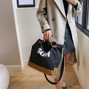 Detail view of the black canvas tote bag with Sun logo and adjustable shoulder strap