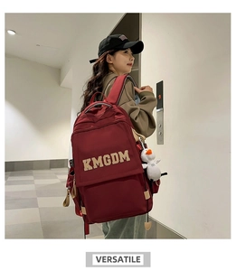 Detail of burgundy nylon backpack with KMGDM embroidery and plush duckling charm pendant