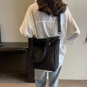 Sac fourre-tout noir minimaliste imperméable avec bandoulière réglable et poche zippée avant