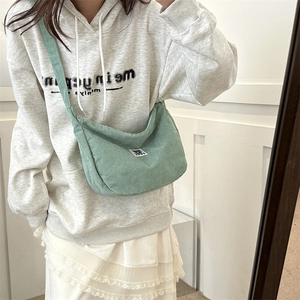 Pale green corduroy crossbody bag with cute bear patch detail in a lifestyle setting