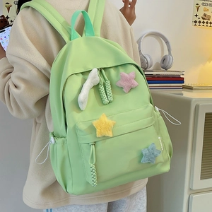 Détail d'un sac à dos en nylon vert avec des étoiles en peluche et un nuage sur la poche