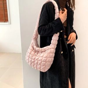 Macro side view of light pink quilted puffy cloud bag with soft cotton padding texture