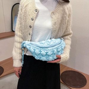 Détail d'un sac bandoulière bleu clair matelassé avec texture nuage porté par un mannequin