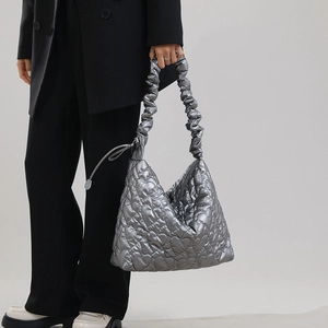 Detail of silver quilted handbag with heart patterns and ruched shoulder strap