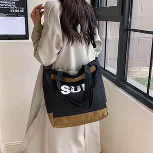 Detail view of canvas tote bag with contrast stitching and SU print on a model