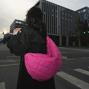 Vue de rue d'un grand sac bandoulière matelassé en nylon magenta sur un mannequin