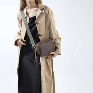 Vue détaillée du sac bandoulière marron avec sangle brodée et pompon en cuir élégant