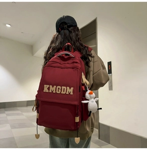 Detailed view of burgundy nylon backpack with KMGDM embroidery and duck toy charm