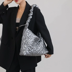 Silver quilted hobo bag with heart patterns worn by a model in a black blazer