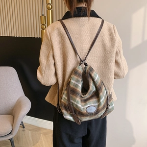 Détail de la texture en laine rayée et de la bandoulière en cuir marron du sac à main