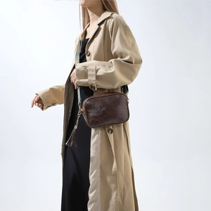 Détail d'un sac bandoulière vintage marron avec bandoulière brodée et pompon en cuir