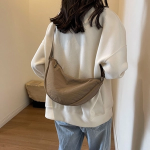 Close-up of minimalist brown crescent crossbody bag featuring premium textured fabric