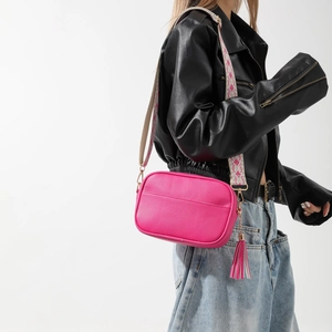 Sac bandoulière rose fuchsia en cuir avec large sangle tissée et gland décoratif