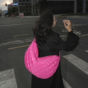 Détail du sac croissant matelassé rose avec coutures en losange et bandoulière large