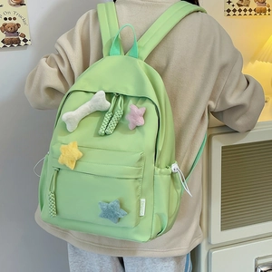 Détail du sac à dos en nylon vert menthe avec écussons mignons en peluche étoile et os