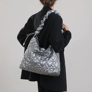 Detail of silver metallic quilted handbag featuring heart patterns and ruffled strap design