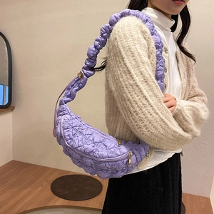 Vue détaillée d'un sac demi-lune matelassé violet porté par un mannequin dans un cadre doux
