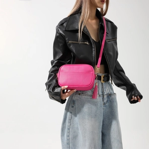 Détail du sac bandoulière rose pêche en cuir grainé avec pompon et dorures