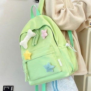 Vue détaillée du sac à dos en nylon vert vif avec charms en peluche os et étoiles