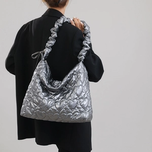 Detailed view of silver quilted heart texture on a metallic nylon shoulder bag
