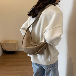 Close-up of khaki crescent crossbody bag on model showing fabric texture and shoulder strap