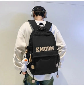 Detail of black nylon backpack with KMGDM embroidery and white plush duck charm