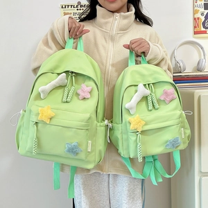 Détail d'un sac à dos en nylon vert clair avec des étoiles en peluche et cordons de zip tissés